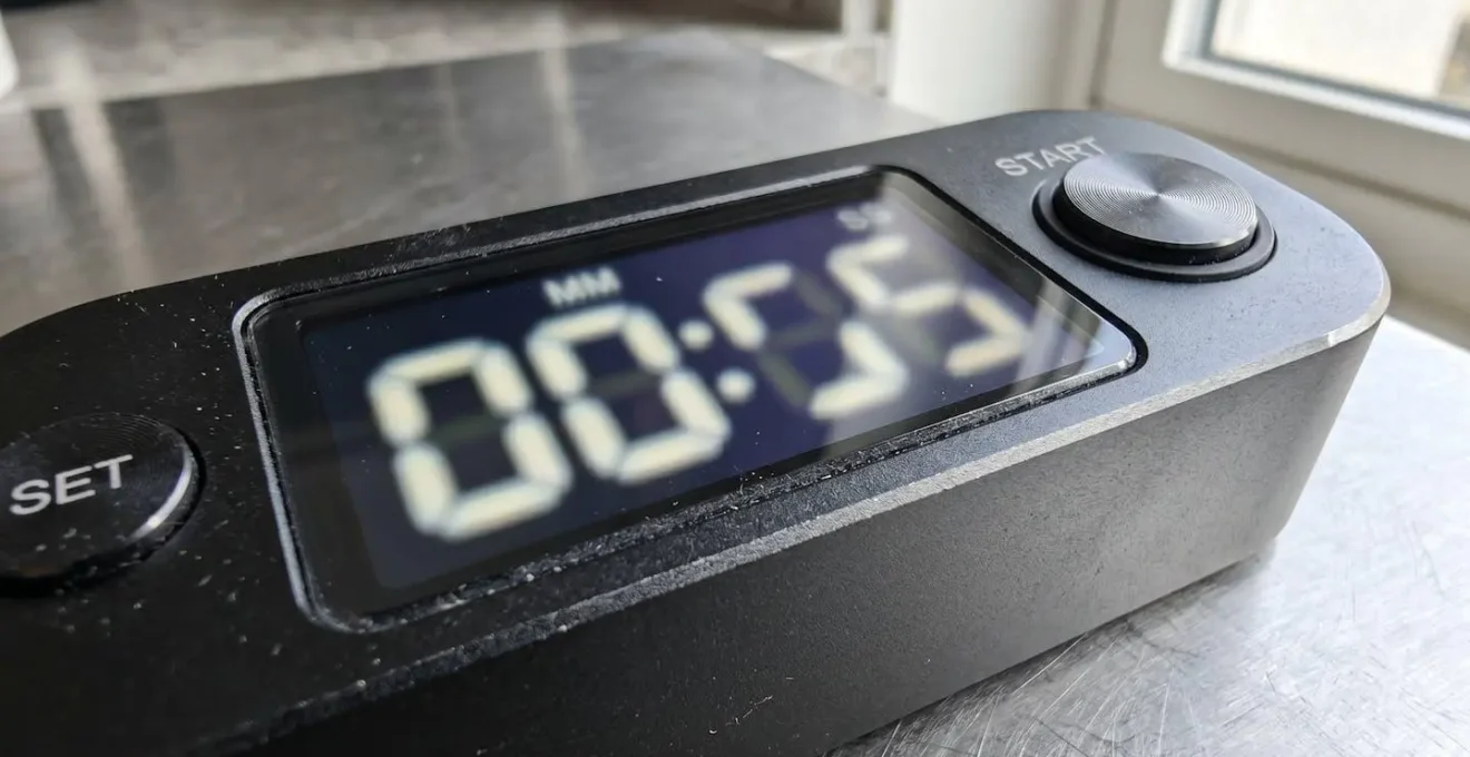 Gros plan en macro sur un chronomètre digital moderne affichant un compte à rebours, fond flouté aux tons chauds